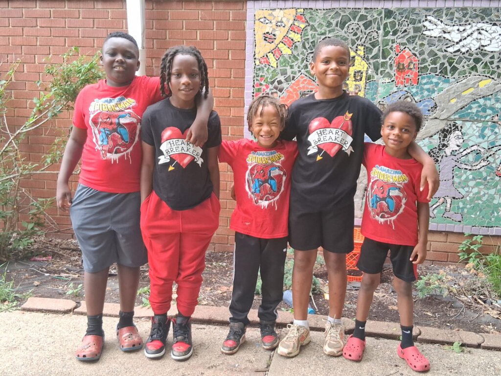 Five children in colorful shirts posing outside